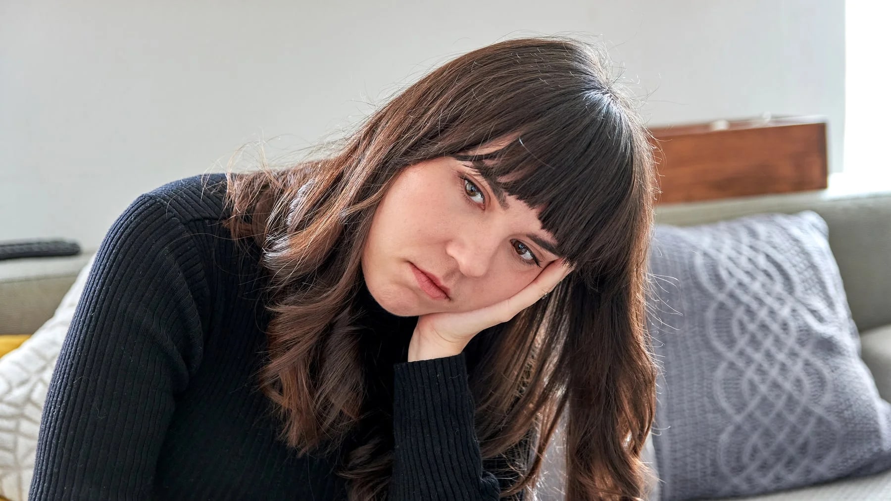 Mulher pensativa com a mão no rosto, num momento de introspecção após uma decepção.