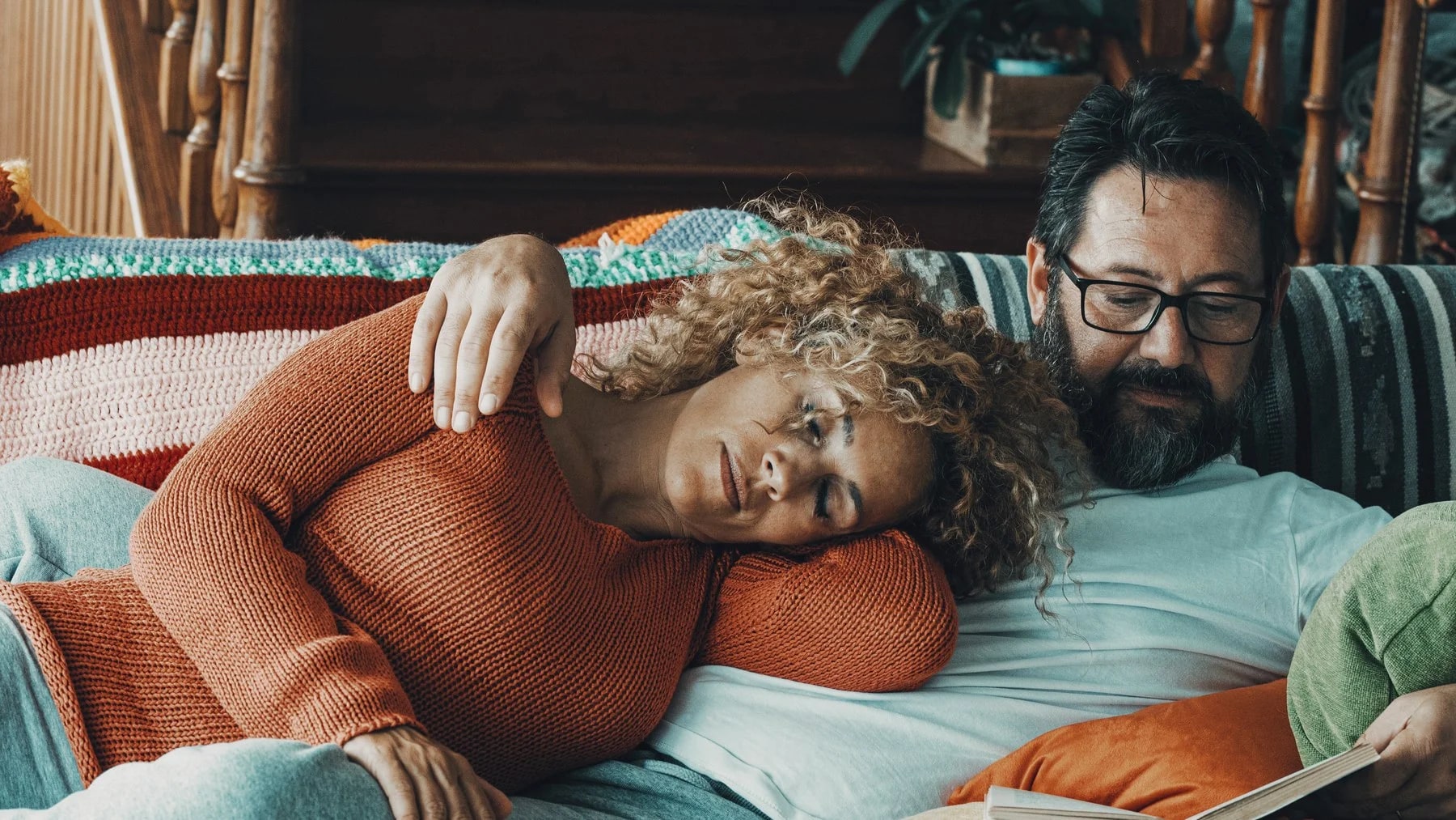 Casal no sofá, ela recostada nele com o olhar distante, ele com a mão na cabeça dela.