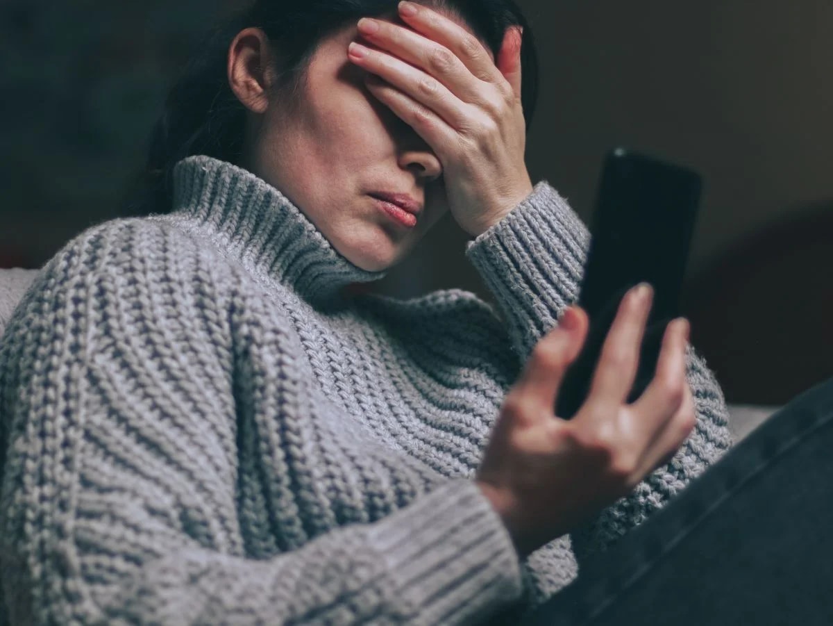 Mulher ansiosa diante do feed do celular avaliando impacto das redes sociais na mente