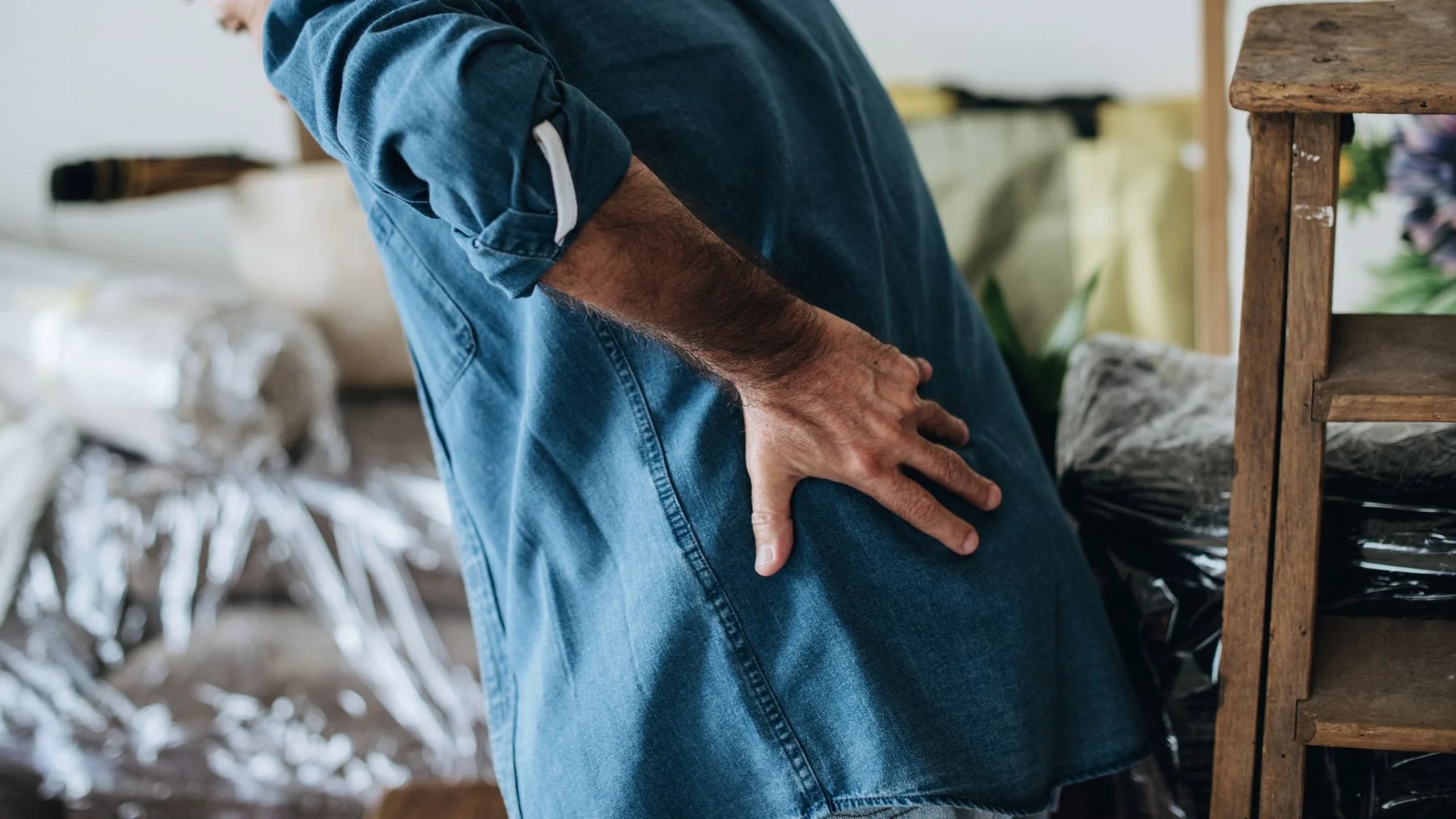 Homem com a mão na lombar, num gesto de dor nas costas durante o dia a dia.