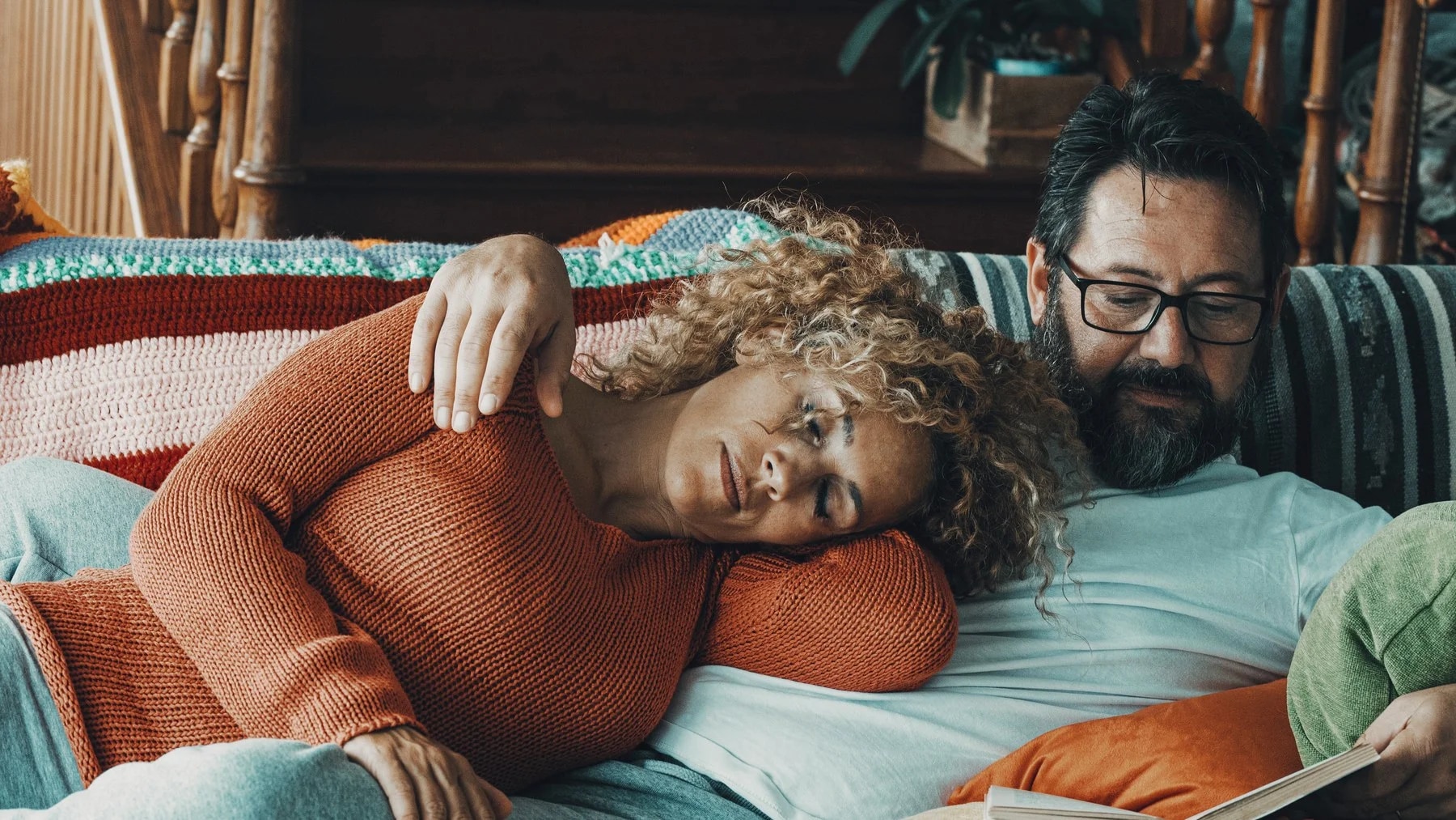 Casal no sofá, ela recostada nele com o olhar distante, ele com a mão na cabeça dela.