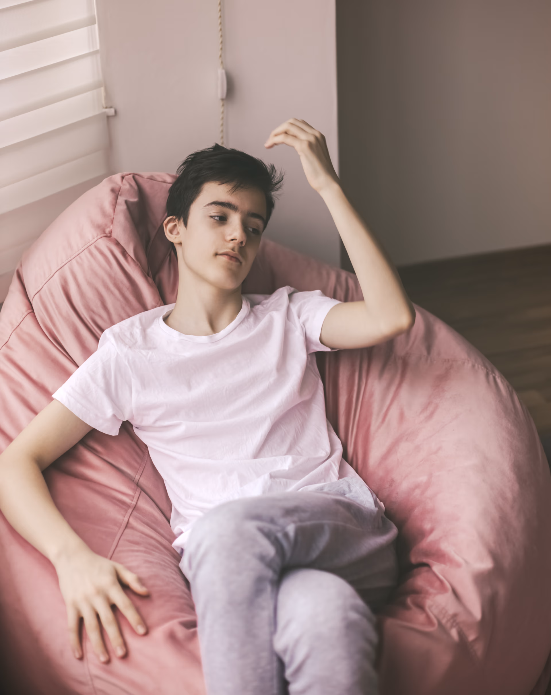 Adolescente recostado em poltrona, olhar tranquilo e disperso. Imagem editorial sobre autismo no Instituto Alceu Giraldi.
