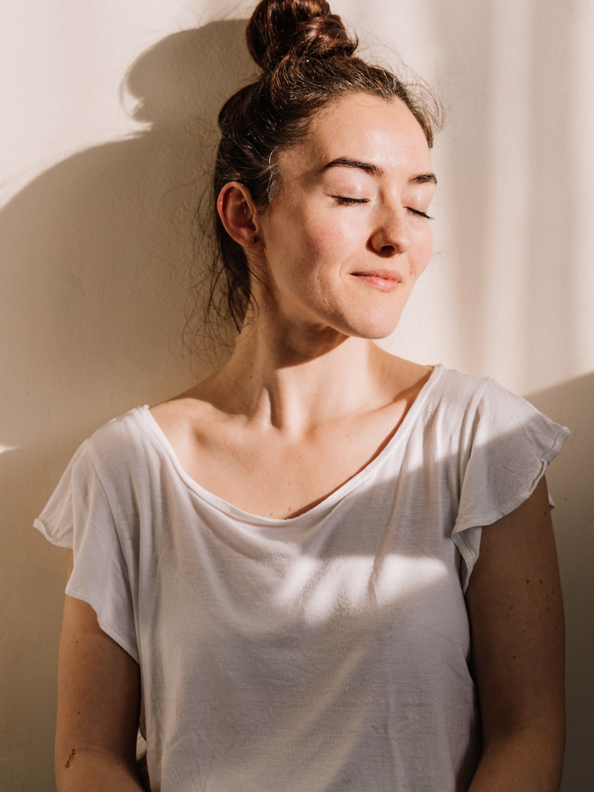 Mulher serena de olhos fechados na luz do sol, imagem editorial sobre tratamento de transtornos alimentares no Instituto Alceu Giraldi.