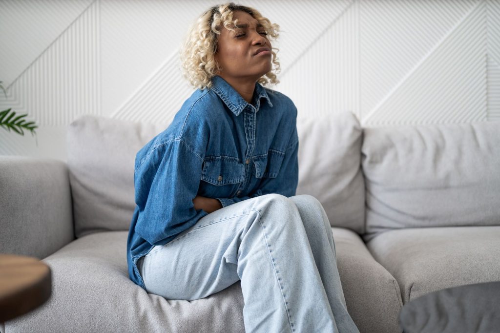 Mulher sofrendo com cólica. TDPM. TPM.